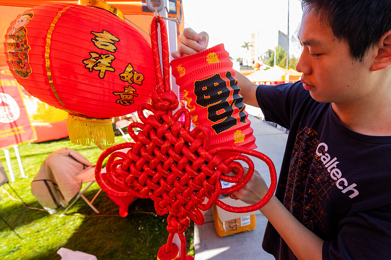 A local resident picks up a red lantern during a fair in Riverside County, California, the United States, January 27, 2024. /CFP