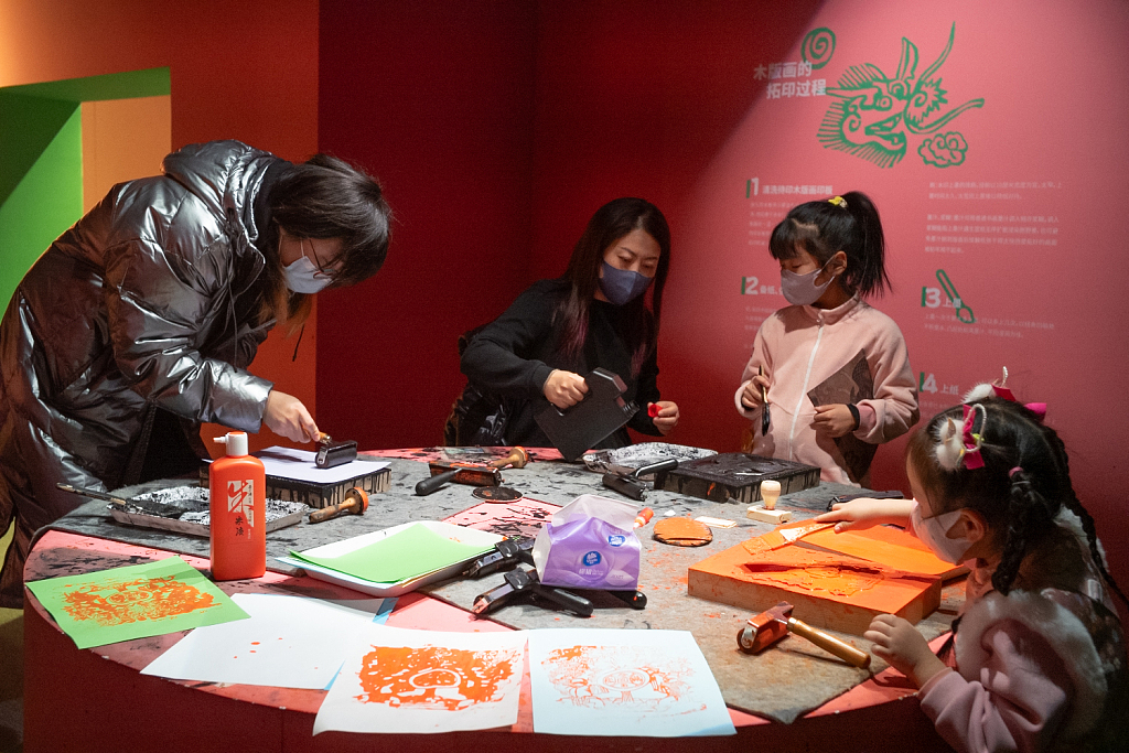 Visitors make loong-shaped woodblock prints at the China Millennium Monument in Beijing during a special exhibition on January 5, 2024. /CFP