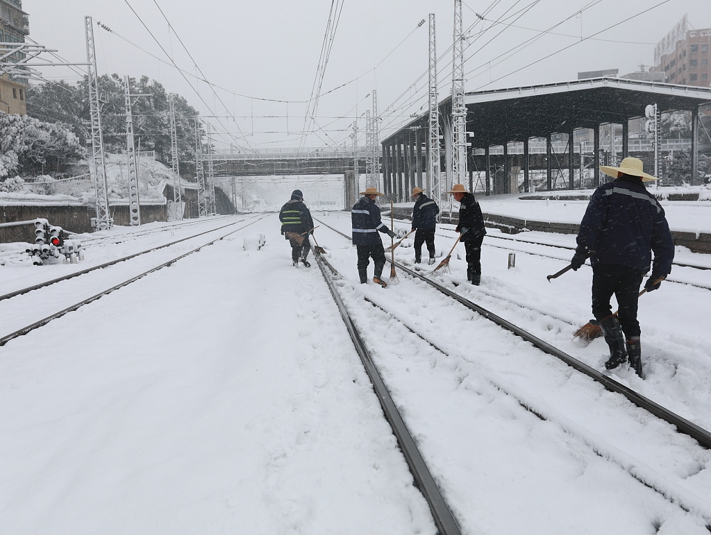 Staff members clear the snow from railway lines at Loudi railway station in central China's Hunan Province, January 22, 2024. /CFP