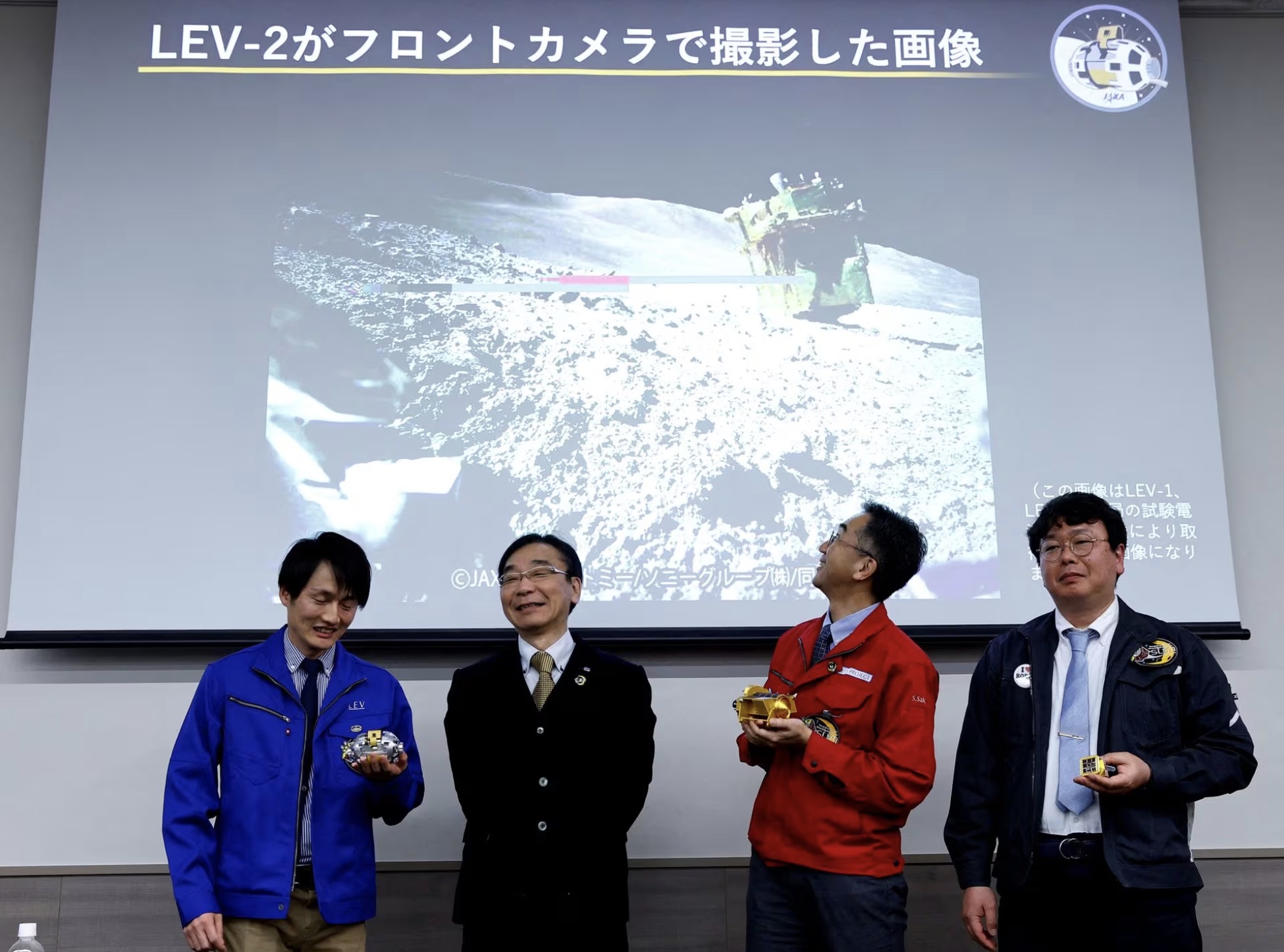 L to R: Daichi Hirano, Hitoshi Kuninaka, Shinichiro Sakai and Masatsugu Otsuki from the Japan Aerospace Exploration Agency, smile in front of a screen showing an image taken by LEV-2 on the moon, after their press conference on SLIM's moon landing mission, in Tokyo, Japan, January 25, 2024. /Reuters