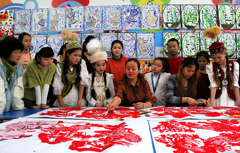 A teacher shows students how to create paper-cutting artworks ahead of the Chinese New Year in Tacheng Prefecture, northwest China's Xinjiang Uygur Autonomous Region, January 29, 2024. /CFP