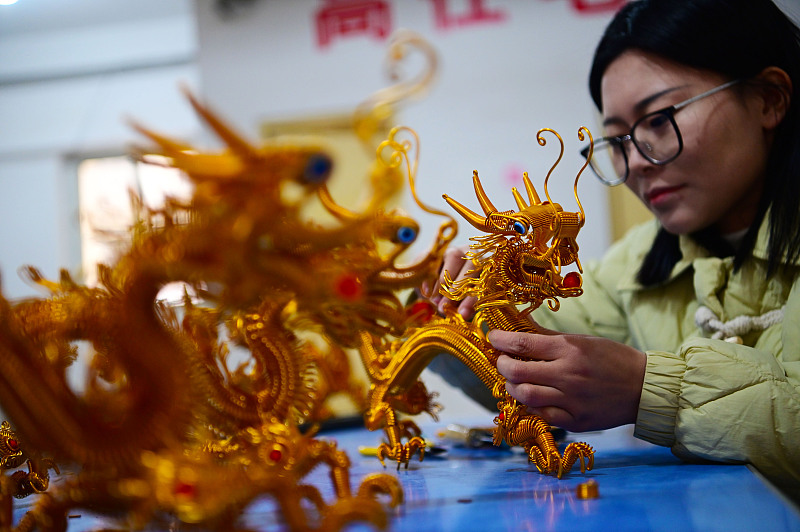 An artisan is busy creating Chinese dragon-shaped artifacts with her bare hands at a workshop in Liaocheng, Shandong Province, January 30, 2024. /CFP