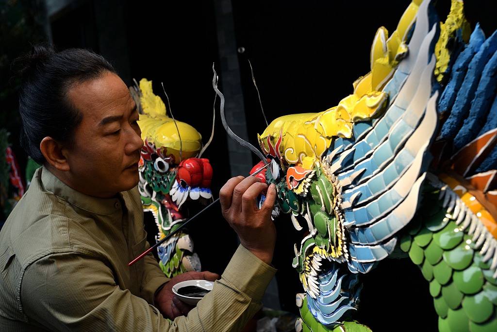 A photo shows inlaid porcelain master Lu Boxin putting the finishing touches on an inlaid porcelain dragon in Chaozhou, Guangdong Province, on January 29, 2024. /CFP