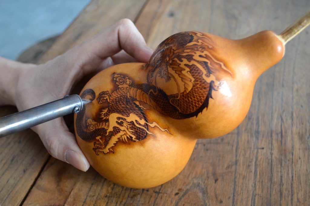A photo shows an artist using a soldering iron to mark a gourd in Jinan, Shandong Province, on January 29, 2024. /IC