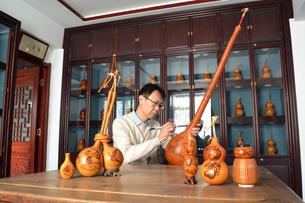A photo shows pyrography artist Li Yaning marking a gourd in Jinan, Shandong Province, on January 29, 2024. /IC