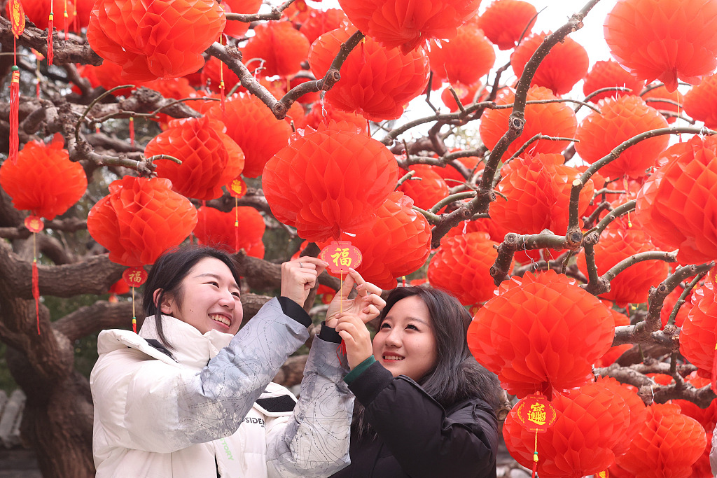 Visitors pose for photos with the festive decorations for the upcoming traditional temple fair at Ditan Park in Beijing on January 30, 2024. /CFP