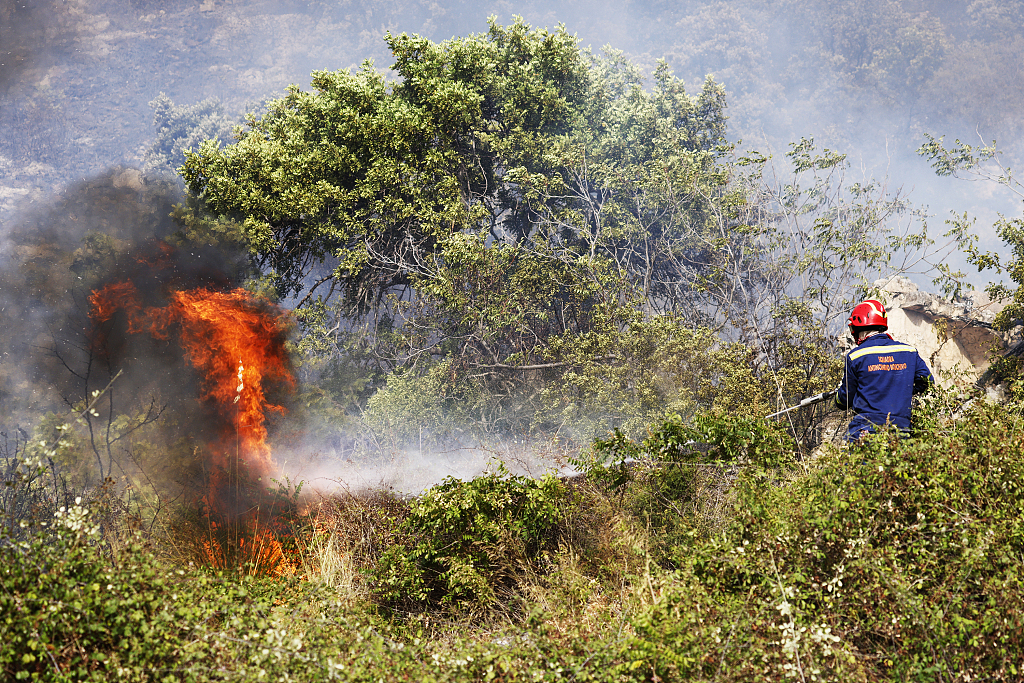 A firefighter sprays water to intervene burning area during wildfire which continues to grow as it started the previous day in the scrub area in Capaci town of Palermo, Italy, July 25, 2023. /CFP