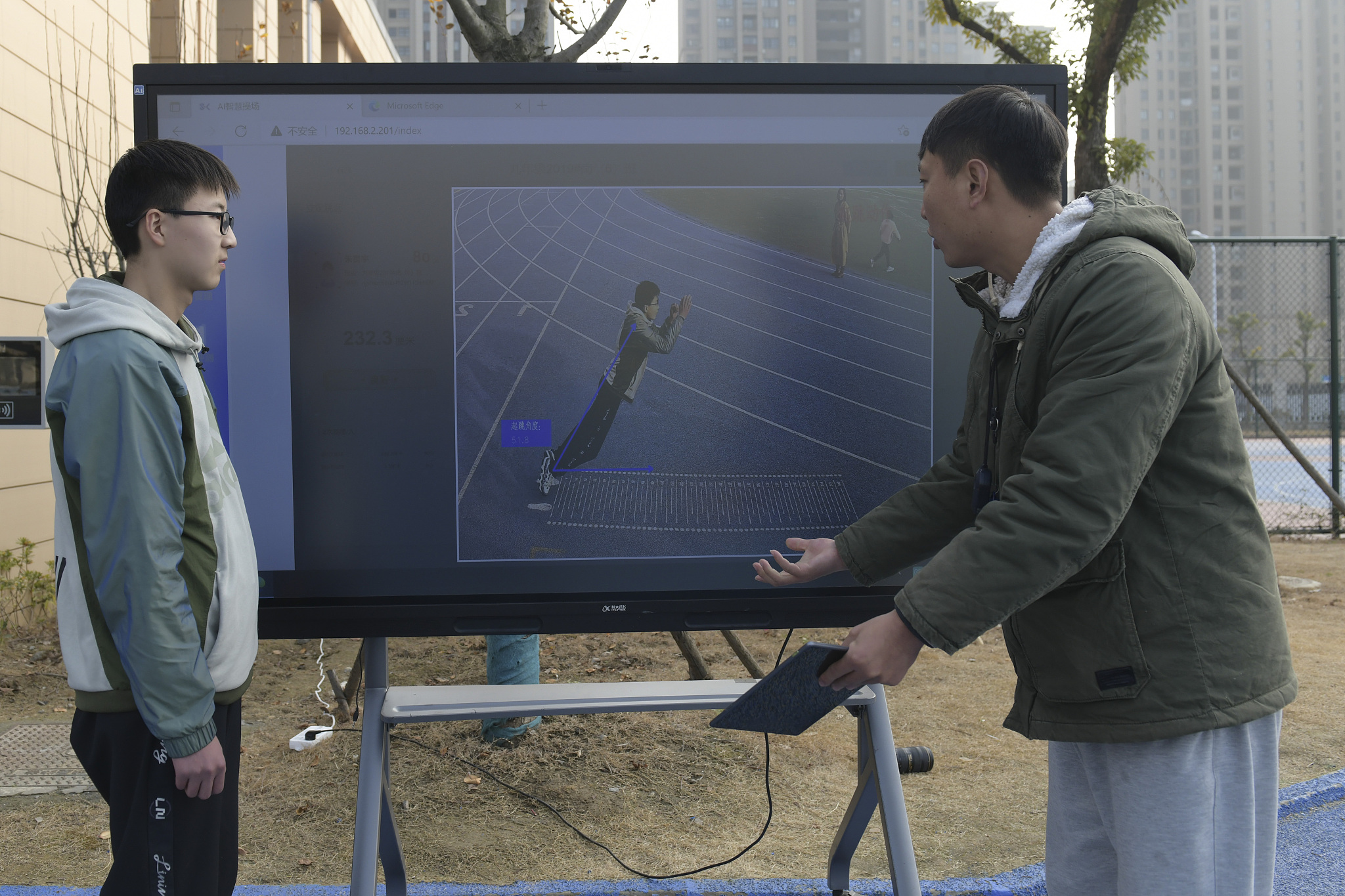 A physical education teacher at a middle school uses a smart playground system to provide feedback and analysis to students following their long jump exercises, Hefei, east China's Anhui Province, January 12, 2022. /CFP