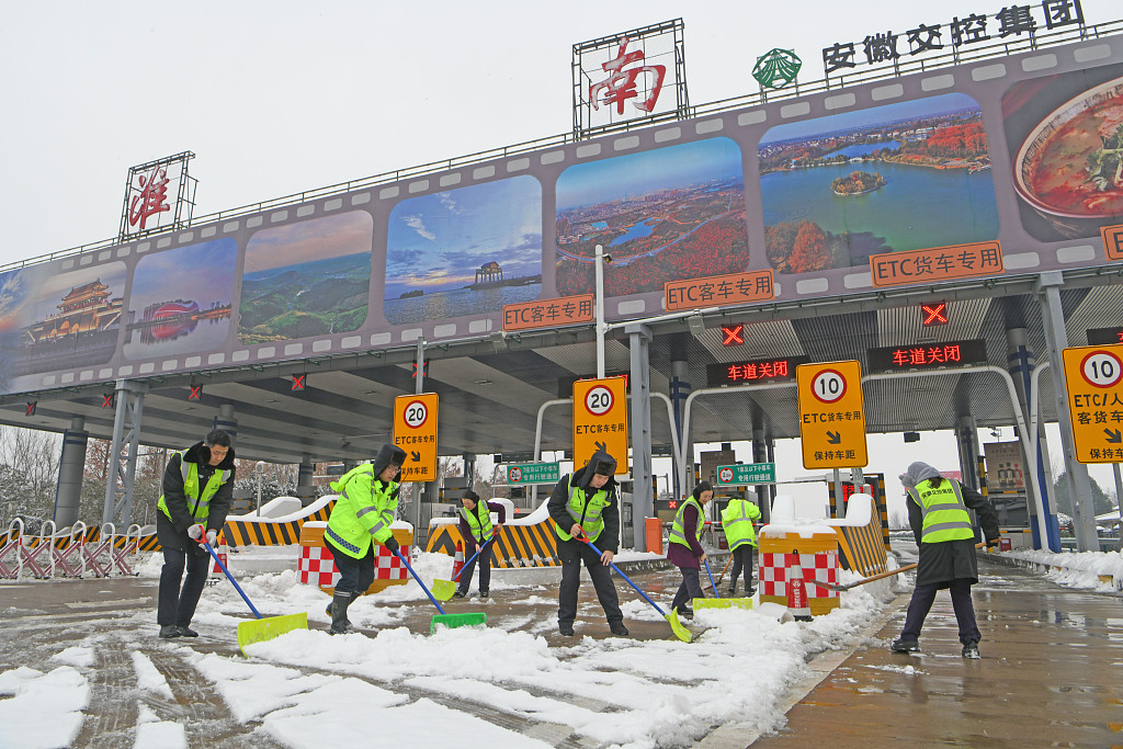 Workers clear the ice and snow at the entrance of an expressway to ensure the traffic safety in east China's Anhui Province, February 2, 2024. /CFP