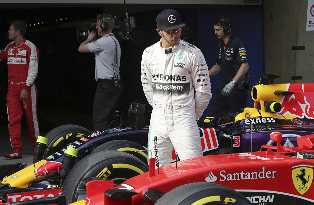 Mercedes driver Lewis Hamilton looks at Finnish driver Kimi Raikkonen's Ferrari after getting pole in the qualifying session for the F1 Chinese Grand Prix at Shanghai International Circuit in Shanghai, China, April 11, 2015. /CFP