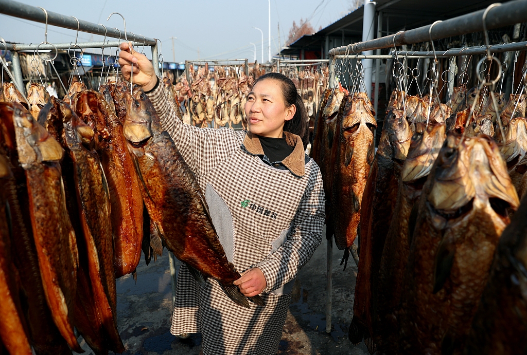 A woman checks on fish being sun-dried on racks in Suqian, east China’s Jiangsu Province, January 29, 2024. /CFP
