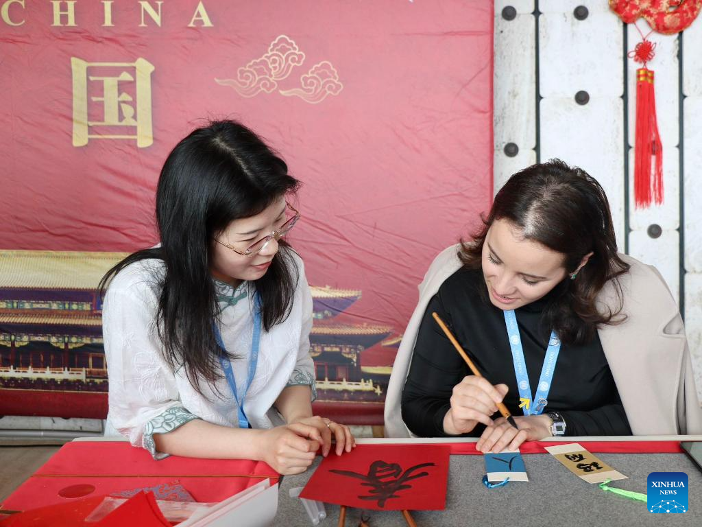 A guest (R) learns to write Chinese characters during an event to celebrate the upcoming Spring Festival in Geneva, Switzerland, February 2, 2024. /Xinhua