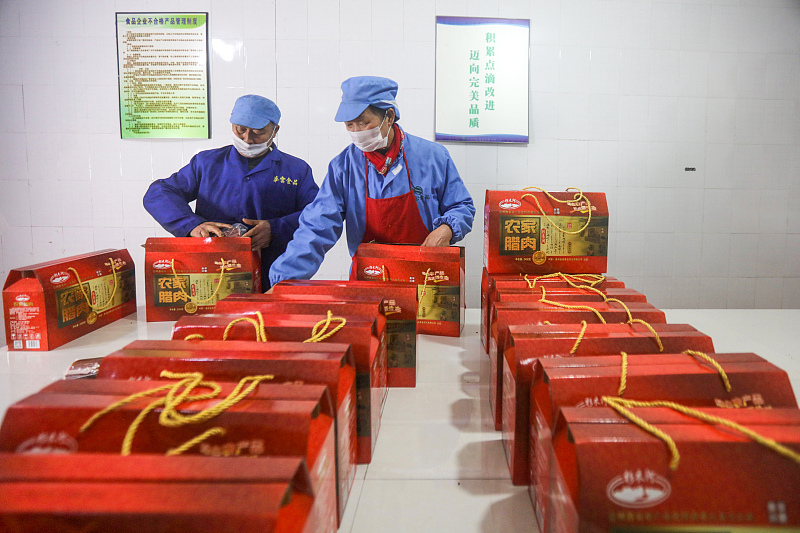 Workers pack local delicacies into gift boxes at a factory in the Qiandongnan Miao and Dong Autonomous Prefecture, Guizhou Province, January 19, 2024. /CFP