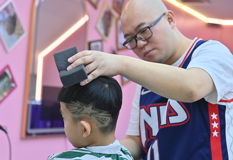 A barber designs a new hairstyle for a boy at a barbershop in Changchun City, Jilin Province, February 4, 2024. /CFP