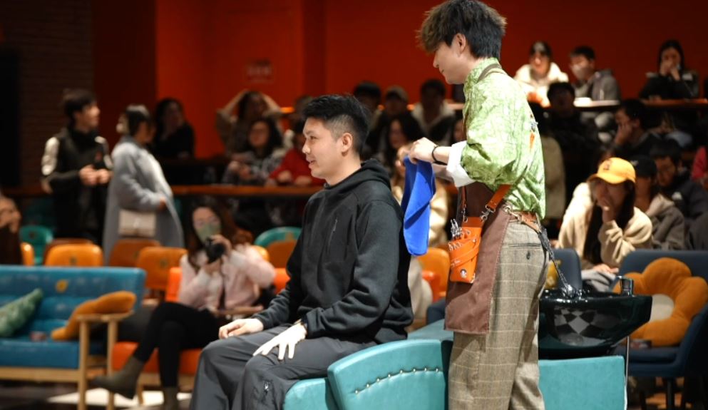 An audience member joins in with the interactive experience of having his hair washed on stage during a live show in Shanghai, January, 2024. /CGTN