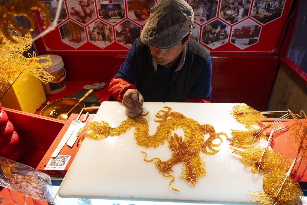A photo shows an artisan making a dragon sugar painting at the Shibati traditional-style scenic area in Chongqing, southwest China, February 5, 2024. /IC