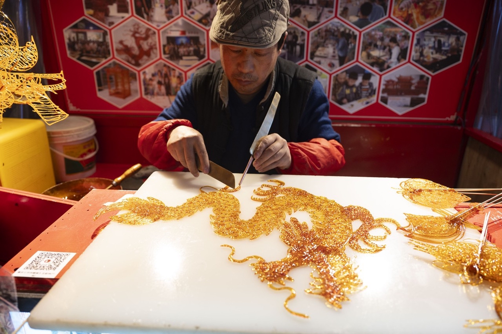 A photo shows an artisan making a dragon sugar painting at the Shibati traditional-style scenic area in Chongqing, southwest China, February 5, 2024. /IC
