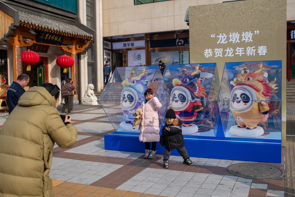 A photo shows children posing with Loong Dwen Dwen installations in Beijing on February 5, 2024. /IC