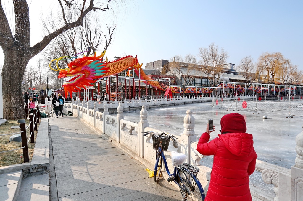 A photo shows a woman taking a picture of a large dragon lantern near the lake at the Shichahai shopping area in Beijing, on February 6, 2024. /IC