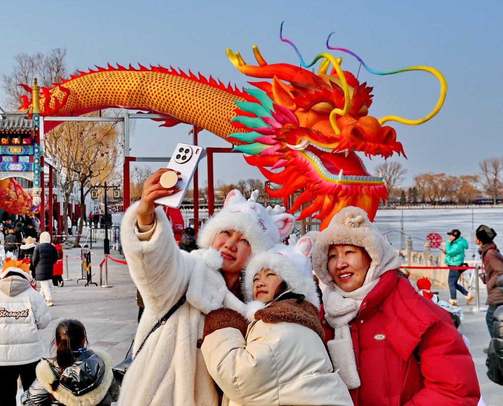 A photo shows people taking a selfie with a large dragon lantern in the Shichahai shopping area in Beijing, on February 6, 2024. /IC