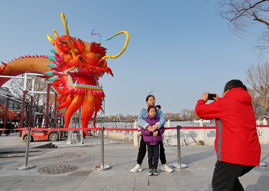 A photo shows people posing for a photo with a large dragon lantern in the Shichahai shopping area in Beijing, on February 6, 2024. /IC
