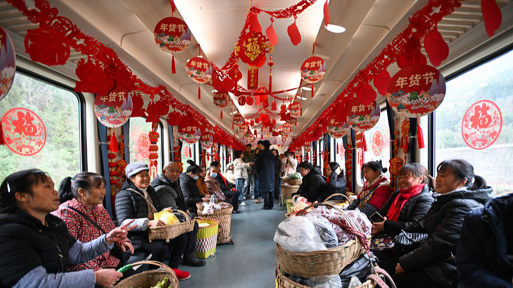 Passengers ride on a train running between southwest China's Chongqing Municipality and Zunyi, Guizhou Province, with New Year decorations hanging on the top of the train, February 5, 2024. /CFP