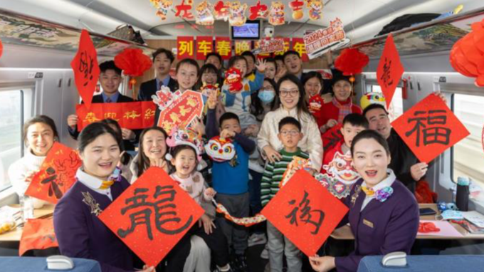 Staff members and passengers pose for photos during a Spring Festival celebration event on the train G1426, February 9, 2024. /Xinhua