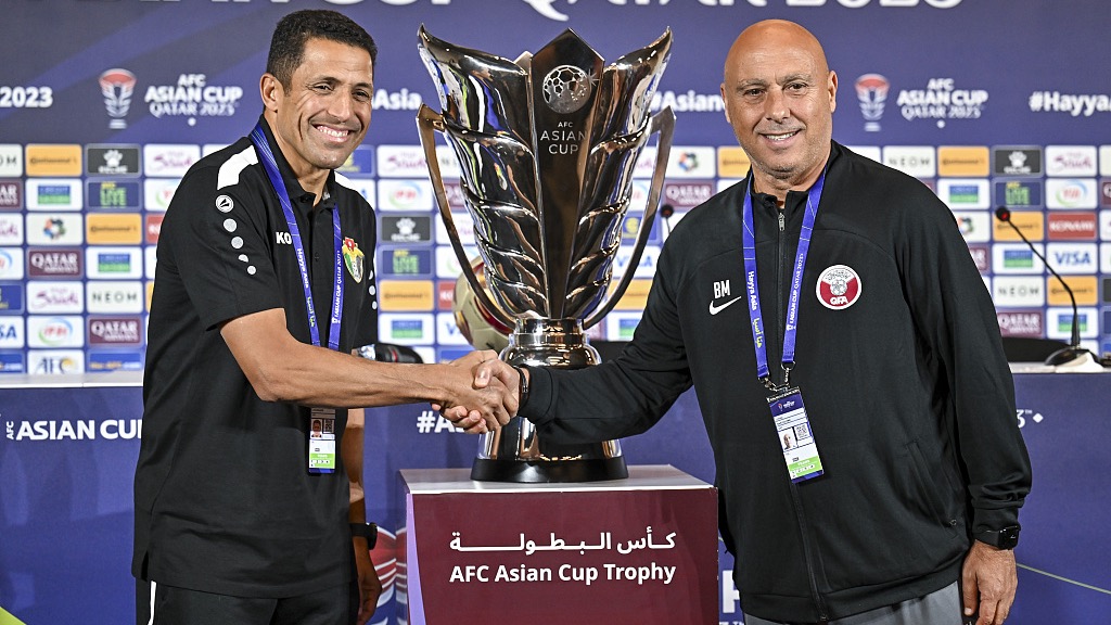 Qatar coach Tintin Marquez (L) and Jordan coach Hussein Amouta shake hands in front of the Asian Cup trophy ahead of the tournament final in Doha, Qatar, February 9, 2024. /CFP