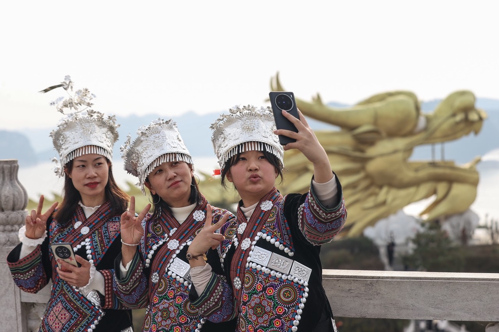 A photo shows visitors taking selfies with the dragon head of a sightseeing corridor in Zunyi, Guizhou Province on February 12, 2024. /IC