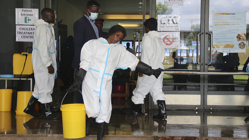 A worker carries a bucket full of disinfectant at a cholera treatment center, in Lusaka, Zambia, January 12, 2024. /CFP