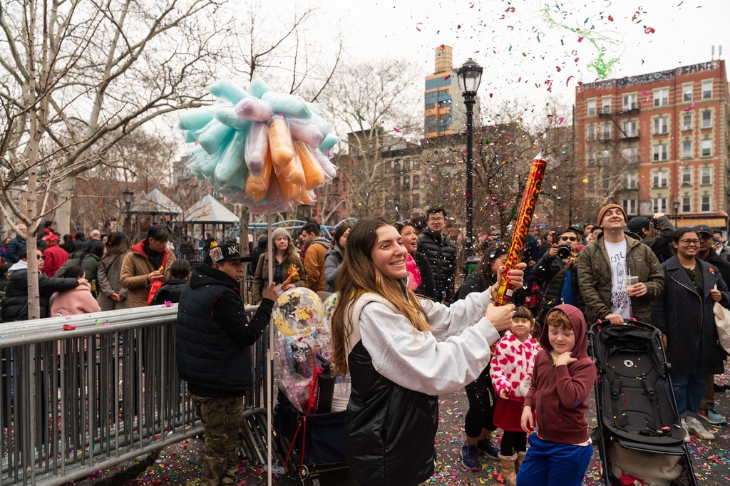 A woman shoots confetti into the air in the streets of Chinatown, New York City, United States, February 10, 2024. /IC