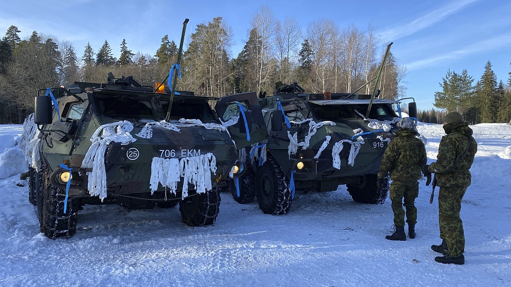 Two Estonian soldiers stand in front of armored personnel carriers on the snowy training ground during a NATO  winter exercise in Tapa, Estonia, February 10, 2024. /CFP