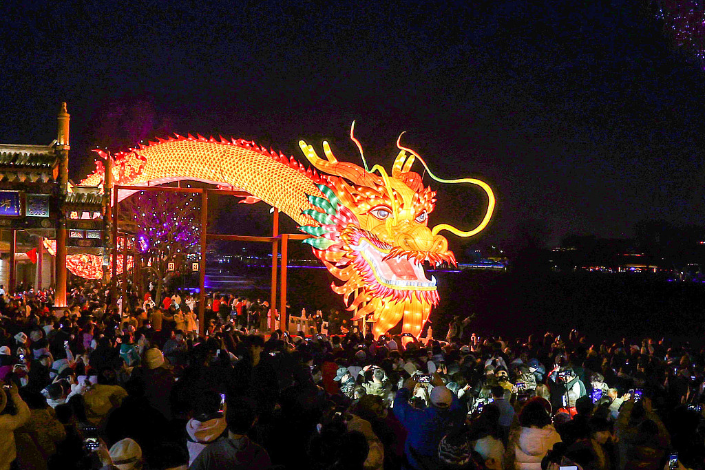 Visitors to the Shichahai scenic area in downtown Beijing take photos of the huge dragon installation on February 13, 2024. /CFP