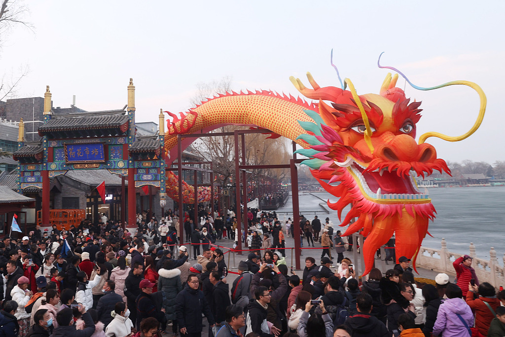 Visitors to the Shichahai scenic area in downtown Beijing take photos of the huge dragon installation on February 13, 2024. /CFP