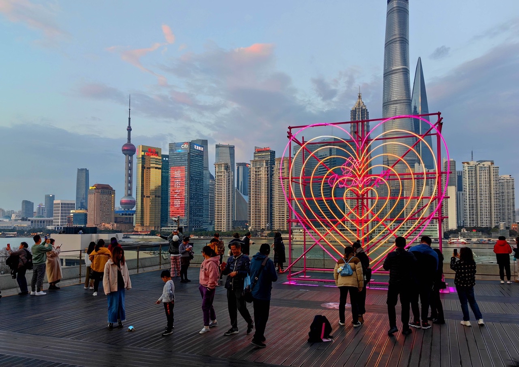 A photo shows visitors admiring the view of a new heart-shaped light installation at the Bund Finance Center in Shanghai, February 13, 2024. /IC