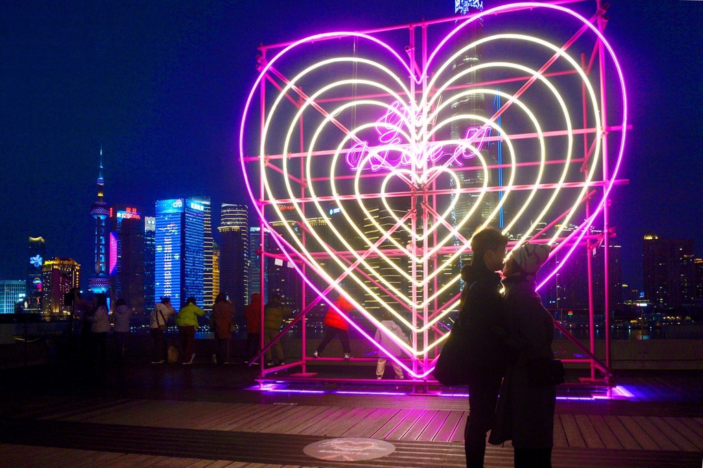 A photo shows a couple sharing a moment in front of a new heart-shaped light installation at the Bund Finance Center in Shanghai, February 13, 2024. /IC