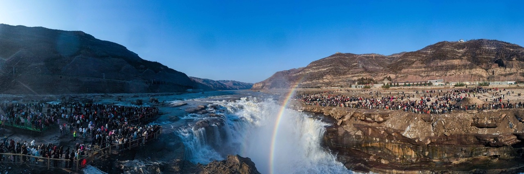 A photo shows visitors on both sides of the Yellow River admiring a rainbow at the Hukou Waterfall in the intersection of Shanxi and Shaanxi provinces, February 13, 2024. /IC