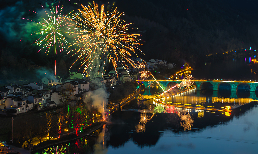 A photo shows fireworks going off as a bamboo raft dragon passes under a bridge in the Qiyun Mountain Scenic Area of Huangshan, Anhui Province, February 12, 2024. /CFP