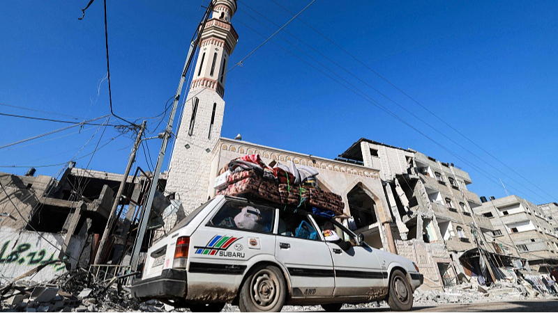A vehicle loaded with belongings secured by rope moves along a street past the rubble of a destroyed building and a mosque minaret in Rafah in the southern Gaza Strip, February 14, 2024. /CFP