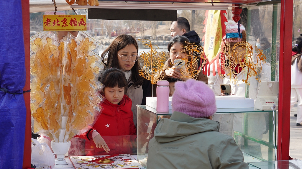 Visitors enjoy sugar painting at Old Summer Palace, Beijing, February 16, 2024. /CFP