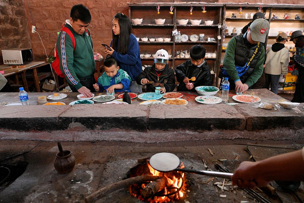 Children and their parents experience making salts in a shop in Chuxiong Yi Autonomous Prefecture, southwest China's Yunnan Province, February 14, 2024. /CFP 