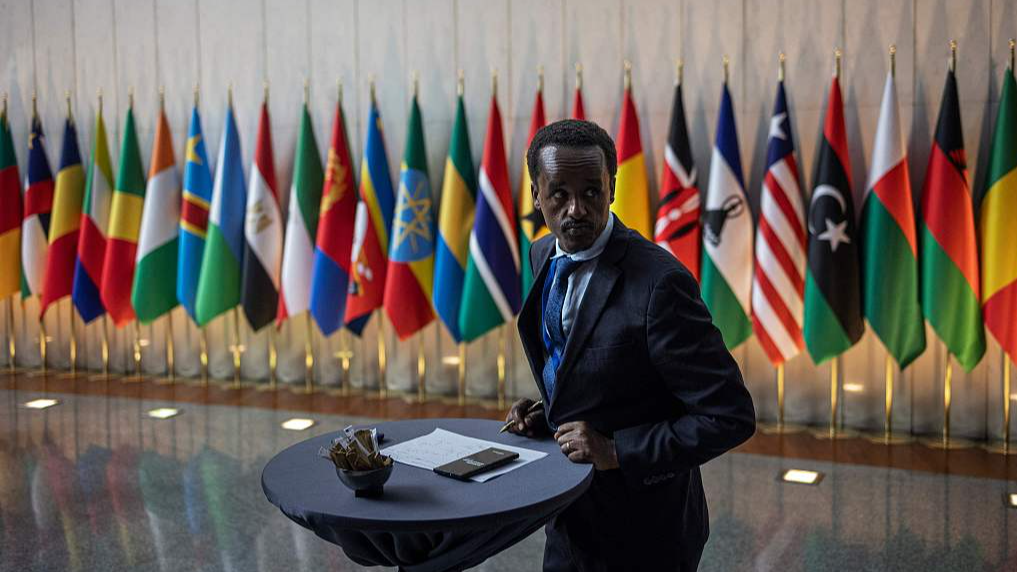 A man takes notes at a table in front of the flags of the member states of the African Union (AU) at the AU headquarters in Addis Ababa, Ethiopia, February 15, 2024. /CFP