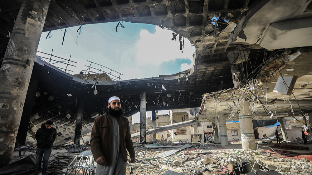 Palestinians walk by rubble near the exposed ceiling of a mosque that was destroyed during an Israeli bombardment, Rafah in southern Gaza, February 16, 2024. /CFP