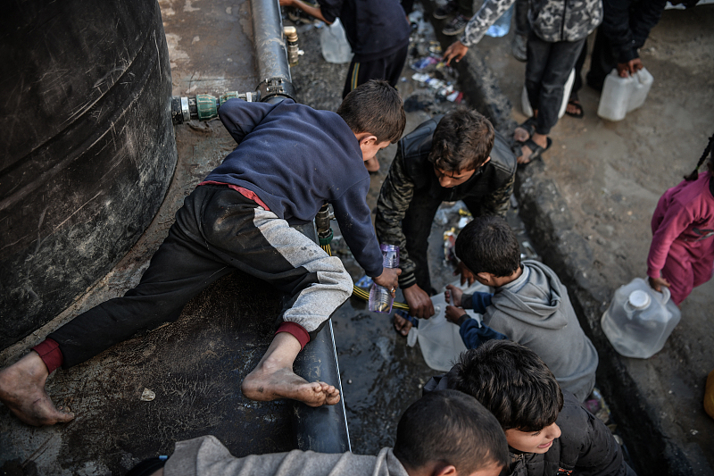 Palestinian children fill up bottles with water distributed by charitable organizations as accessing clean water gets harder due to the ongoing Israeli blockade, in Rafah, Gaza, February 16, 2024. /CFP