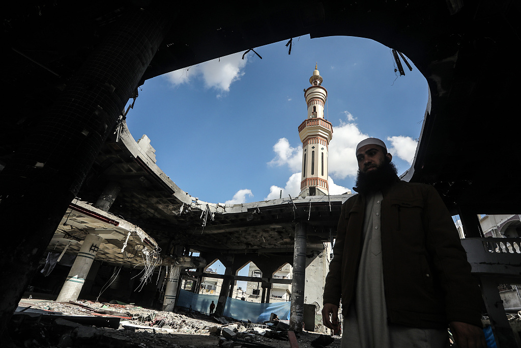Palestinians walk amid rubble near the exposed ceiling of a mosque that was destroyed during Israeli bombardment, in Rafah in southern Gaza, February 16, 2024. /CFP