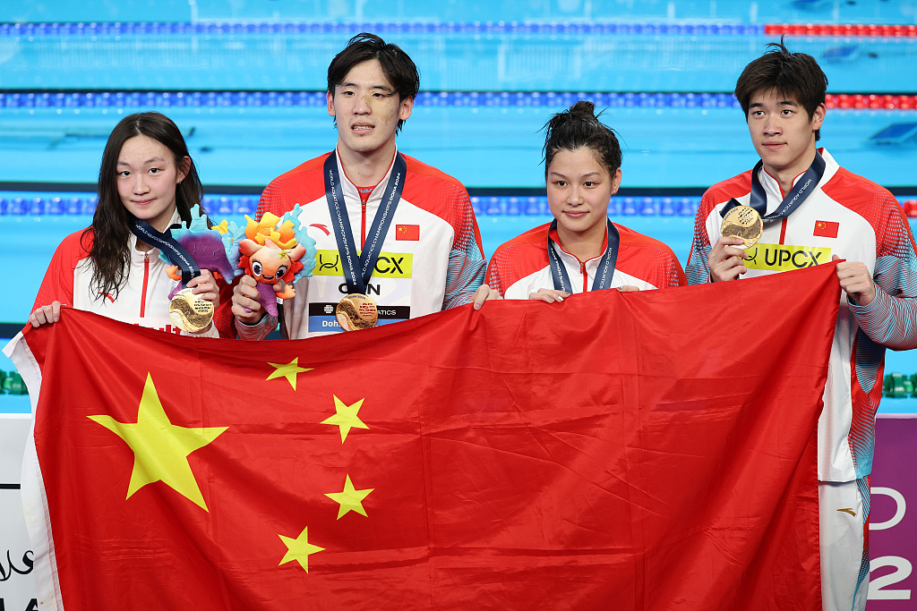 L-R: Li Bingjie, Wang Haoyu, Yu Yiting, and Pan Zhanle jointly hold the national flag of China after winning the gold medal in the mixed 4x100m freestyle relay final during the World Aquatics Championships in Doha, Qatar, February 17, 2024. /CFP