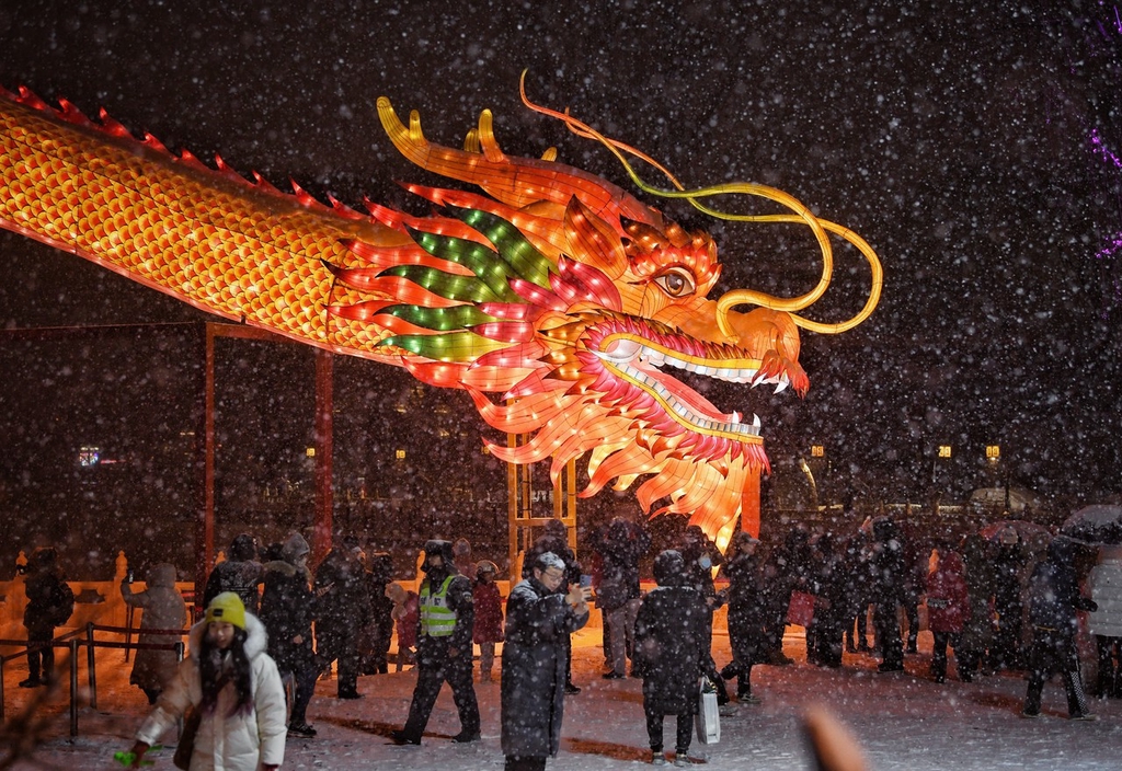 A photo shows the head of a 200-meter-long dragon lantern glowing during snowfall in the Shichahai shopping area in Beijing, February 20, 2024. /IC