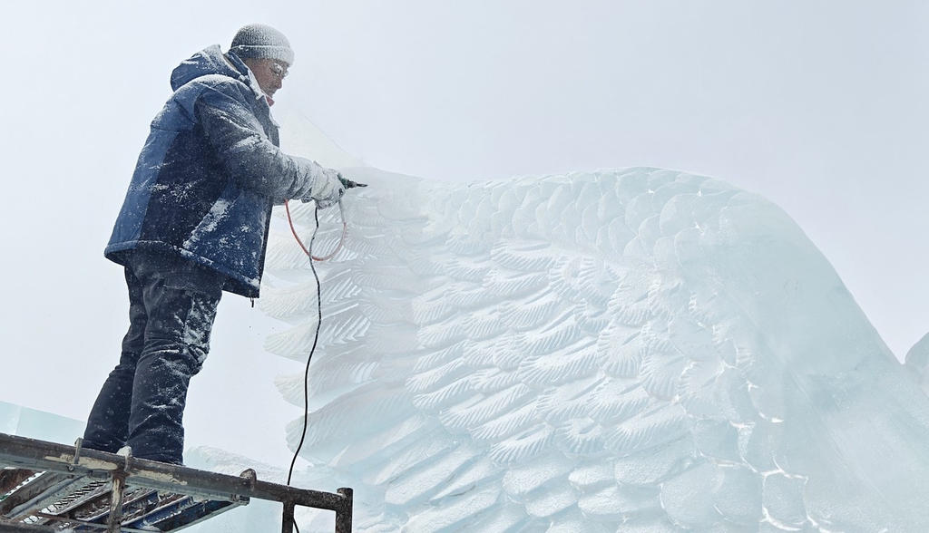 A sculptor carves the wing of an ice work in Changchun, northeast China's Jilin Province, February 20, 2024. /IC