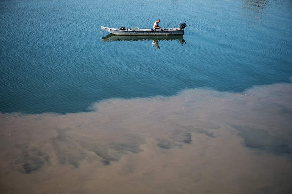 An angler sits in a boat on the Sava River in Belgrade near a sewage output, October 23, 2019. /CFP