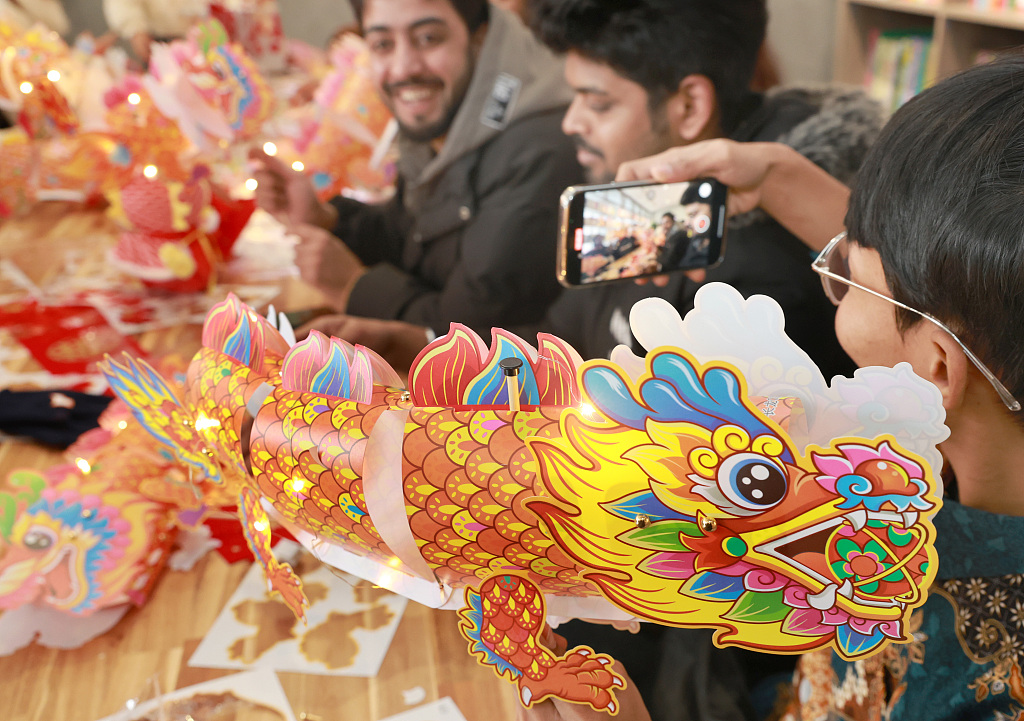 A student is seen taking a photo of other students making dragon lanterns in Nantong, east China's Jiangsu Province, February 23, 2024. /CFP